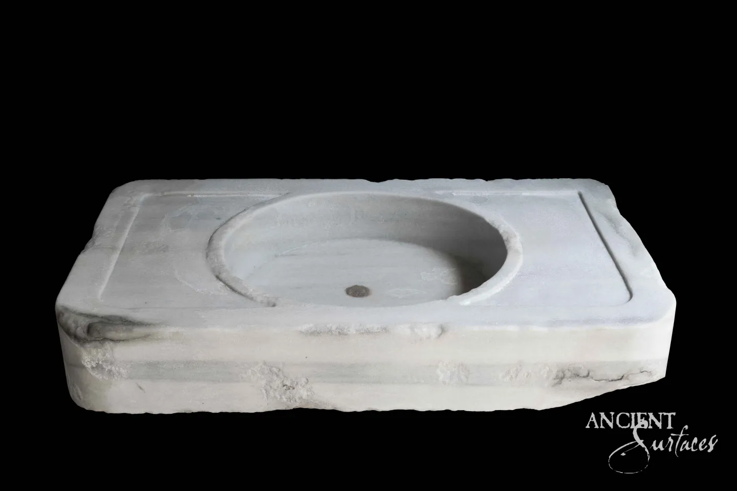 Antique white marble sink by Ancient Surfaces carved from a single block with a shallow oval basin and chiselled edges