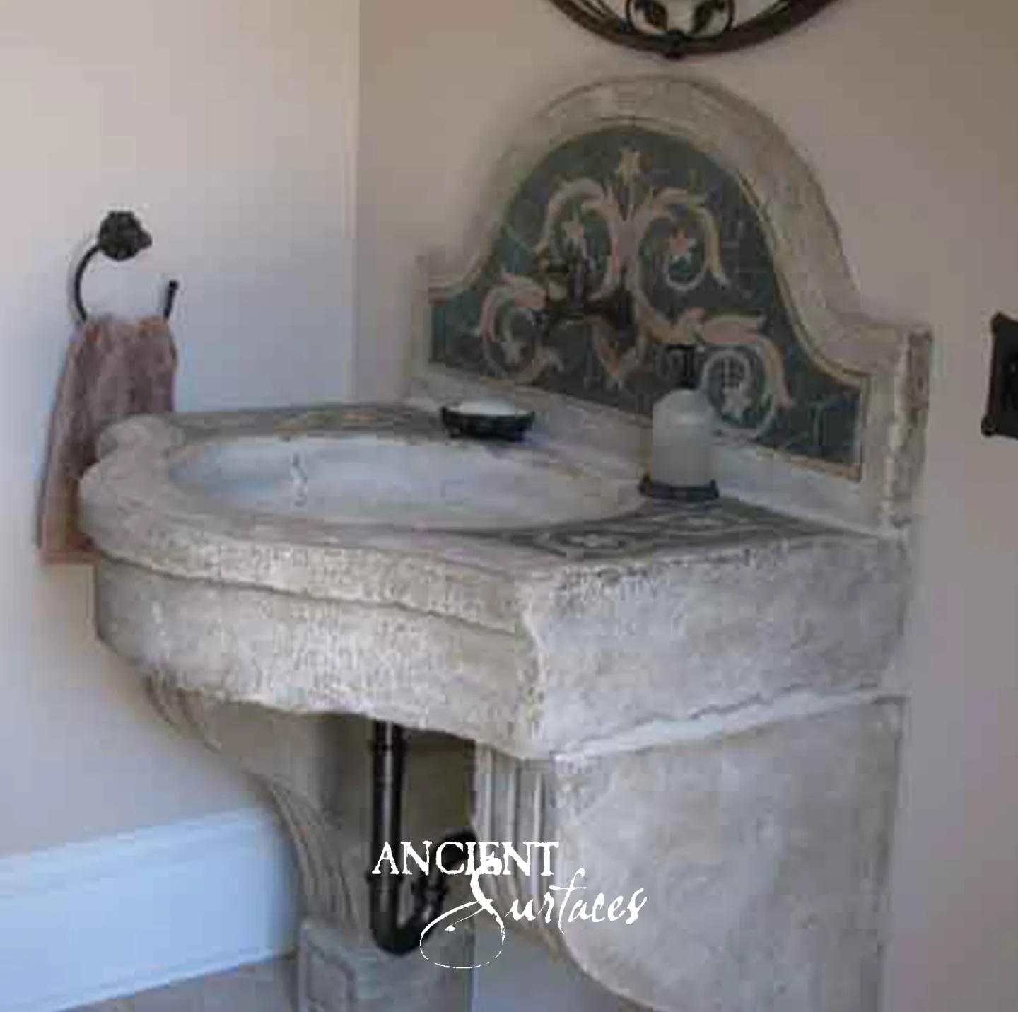Carved antique limestone corner sink by Ancient Surfaces with a hand painted stone mosaic backsplash in a powder room